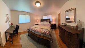 A bedroom with a bed, bedside tables, a dresser, a mirror, and a window with blinds. - Manito South Spokane Guest House (Spokane)