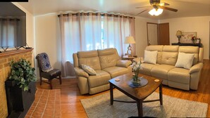 A living room with a beige sofa, a wooden coffee table, and a TV mounted on the wall. - Manito South Spokane Guest House (Spokane)