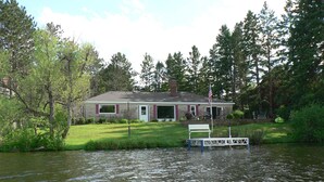A house by a lake with a dock and a lawn chair.