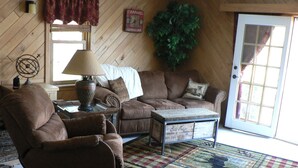 A cozy living room with a brown leather sofa, a matching armchair, a coffee table, and a patterned rug.