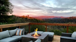 Une terrasse dotée d’un foyer extérieur, de sièges et offrant une vue sur les montagnes.