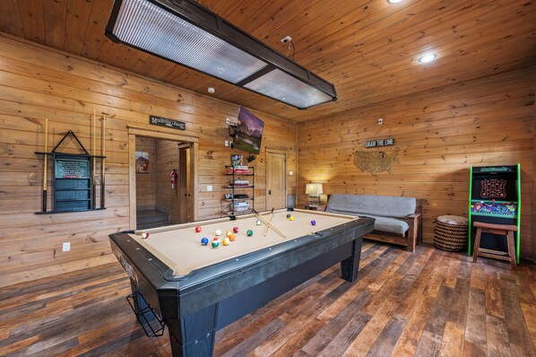 Una mesa de billar con bolas, un sofá, un mapa en la pared y un cartel que dice "Mountain Lodge".