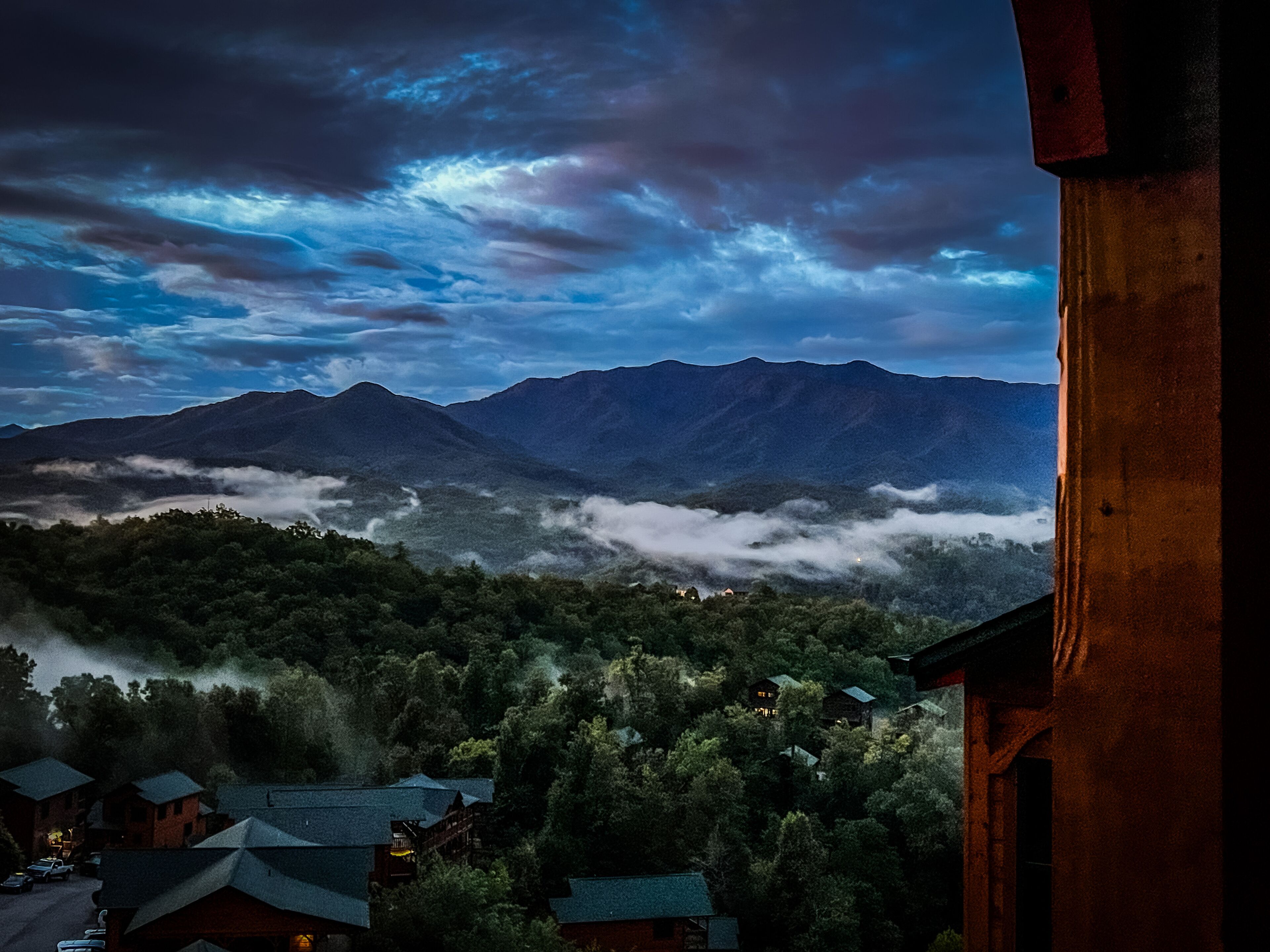 A mountain landscape with a view of the mountains and a forested valley.