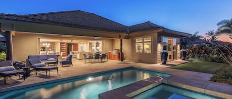 A modern house with a swimming pool, outdoor furniture, and a well-lit patio area.