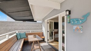 A wooden deck with a bench, table, and a welcome sign.