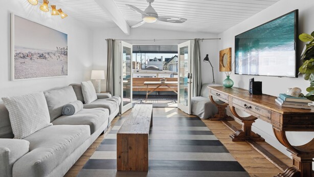 A modern living room with a sofa, coffee table, and a view of the city through a glass door.