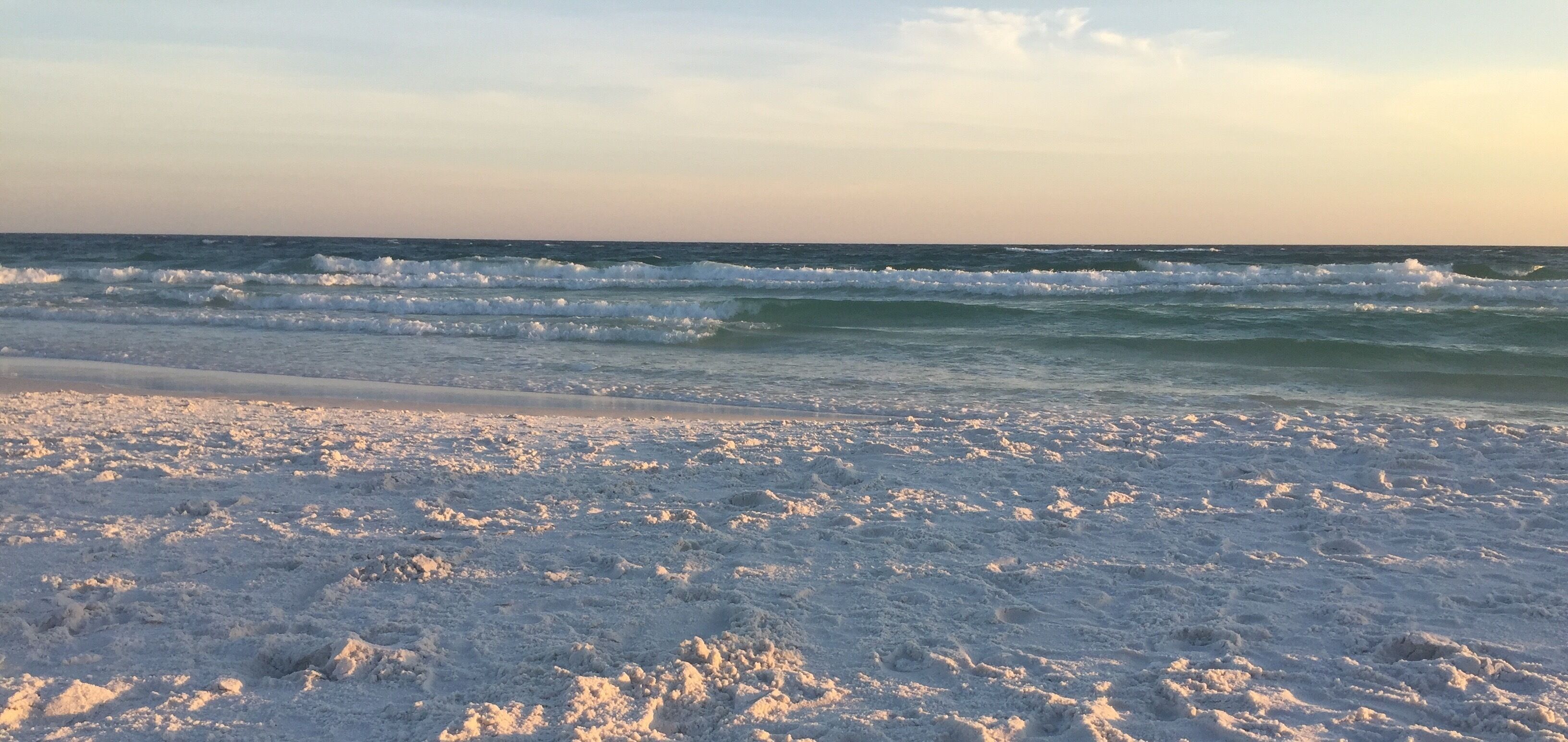 A beach with waves and a clear sky.
