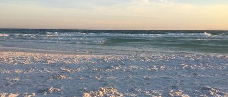 A beach with waves and a clear sky.