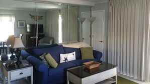 Een moderne woonkamer met een blauwe bank, een glazen salontafel en een televisietoestel.