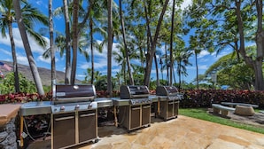 An outdoor barbecue area with stone flooring and multiple Weber grills. - Enjoy Breathtaking Views of the Ocean and Gorgeous Mountains!!! Newly Renovated! (Waianae)