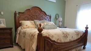 Une chambre à coucher avec un lit en bois, une literie à motifs floraux, une table de chevet et une commode.