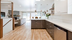 Una cocina moderna con suelo de madera, armarios blancos y lavavajillas integrado.