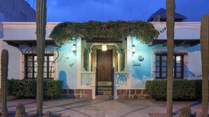 A building with a wooden door, a staircase, and a garden with cacti.