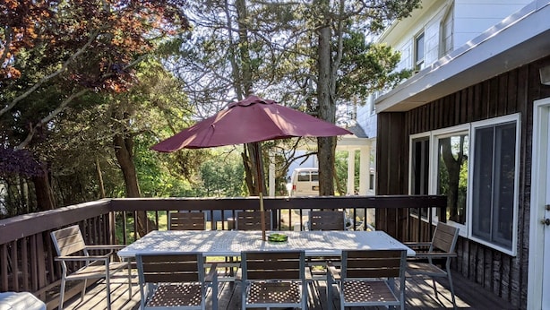 A deck with a table and chairs, a picnic table, and a covered area with an umbrella. - 10 Bedroom Hampton House with a regulation size Pickleball court (Hampton Bays)