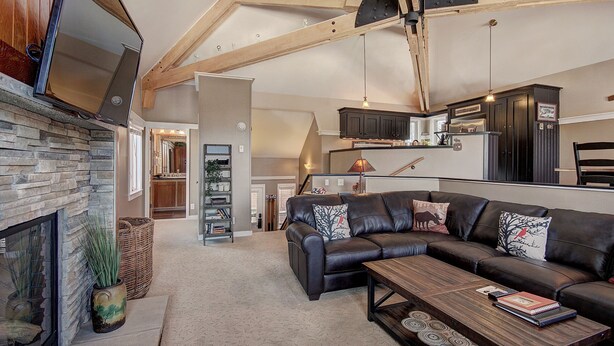A spacious living room with a stone fireplace, a leather sofa, and a wooden coffee table. - Gorgeous Luxury Townhome/Pool and Hot Tub Access (Keystone)