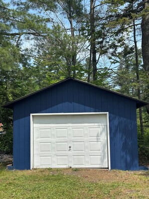 A blue garage with a white door, surrounded by trees. - Private cabin/beach and lake check out water sports all included (Toivola)
