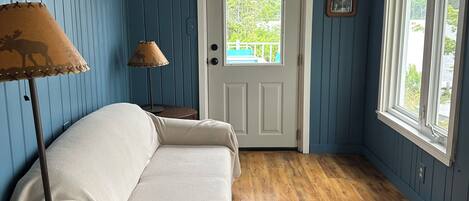 Una habitación con una cama, una lámpara, una puerta y una ventana.