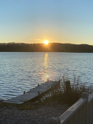 A calm lake with a wooden dock extending into the water, surrounded by trees and a clear sky. - Private cabin/beach and lake check out water sports all included (Toivola)