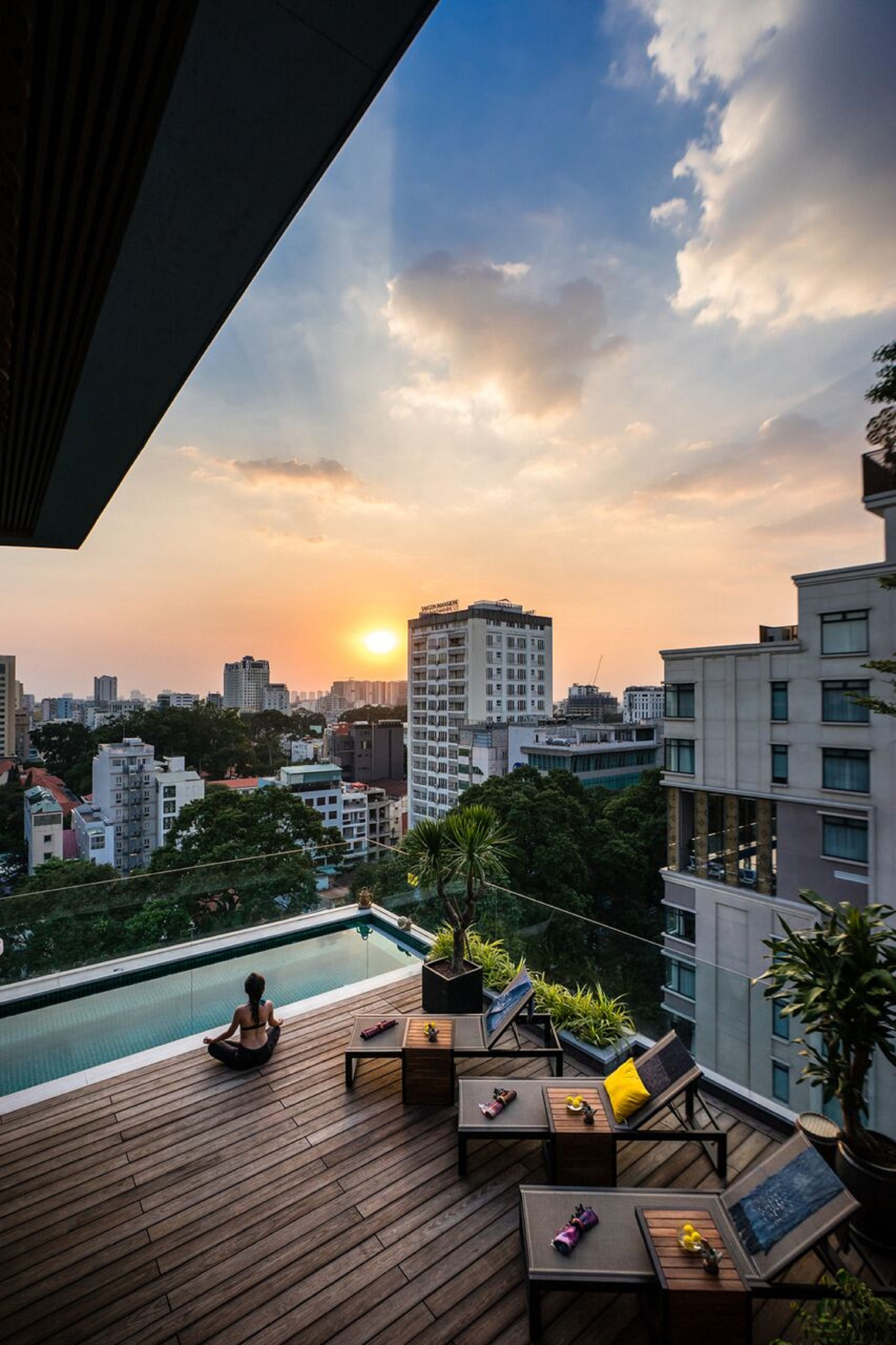 A rooftop terrace with a pool, lounge chairs, and a yoga mat.