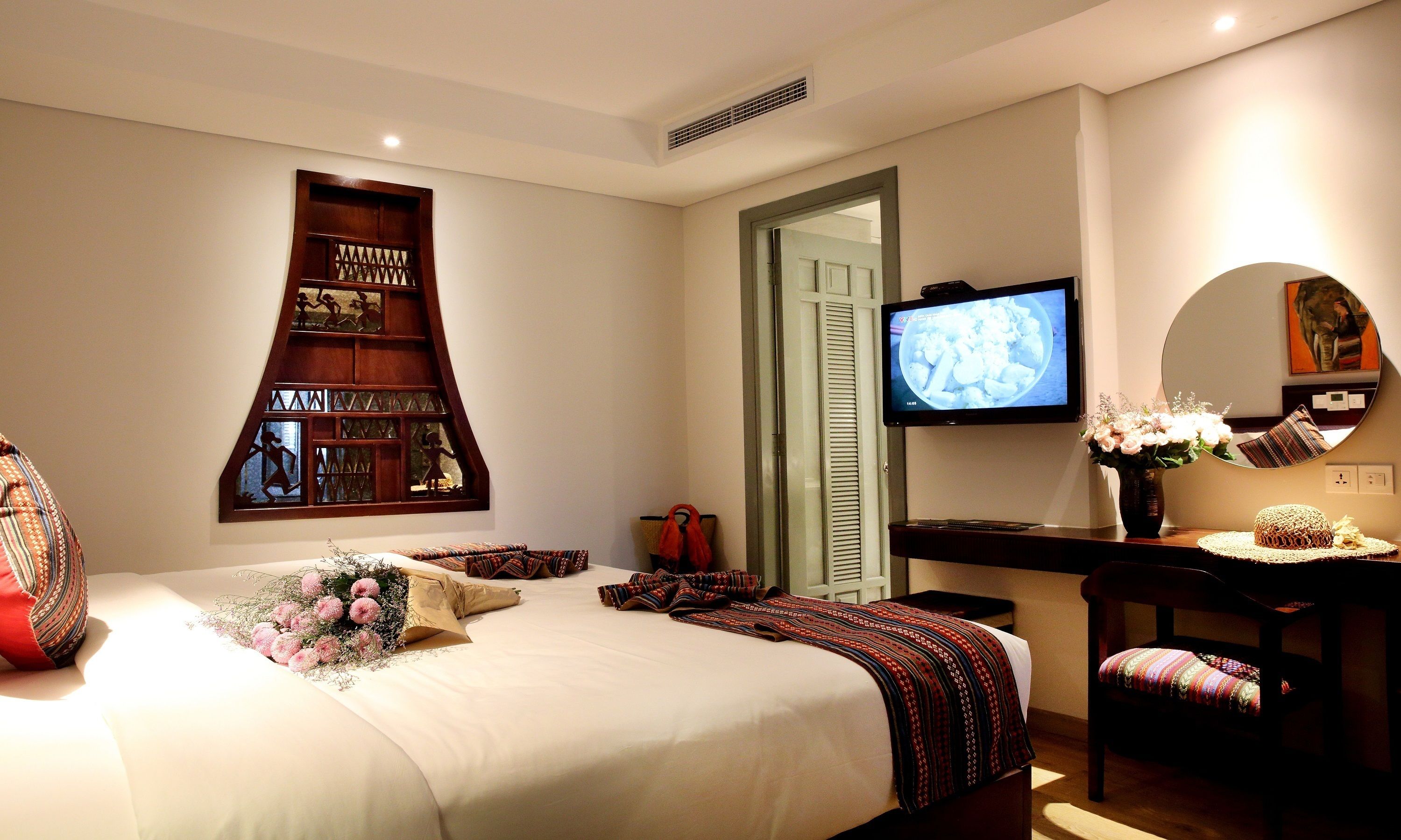 Una habitación de hotel con una cama, televisión, espejo y un adorno en la pared.