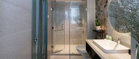A modern bathroom with a glass-enclosed shower, a white sink, and a large mirror.