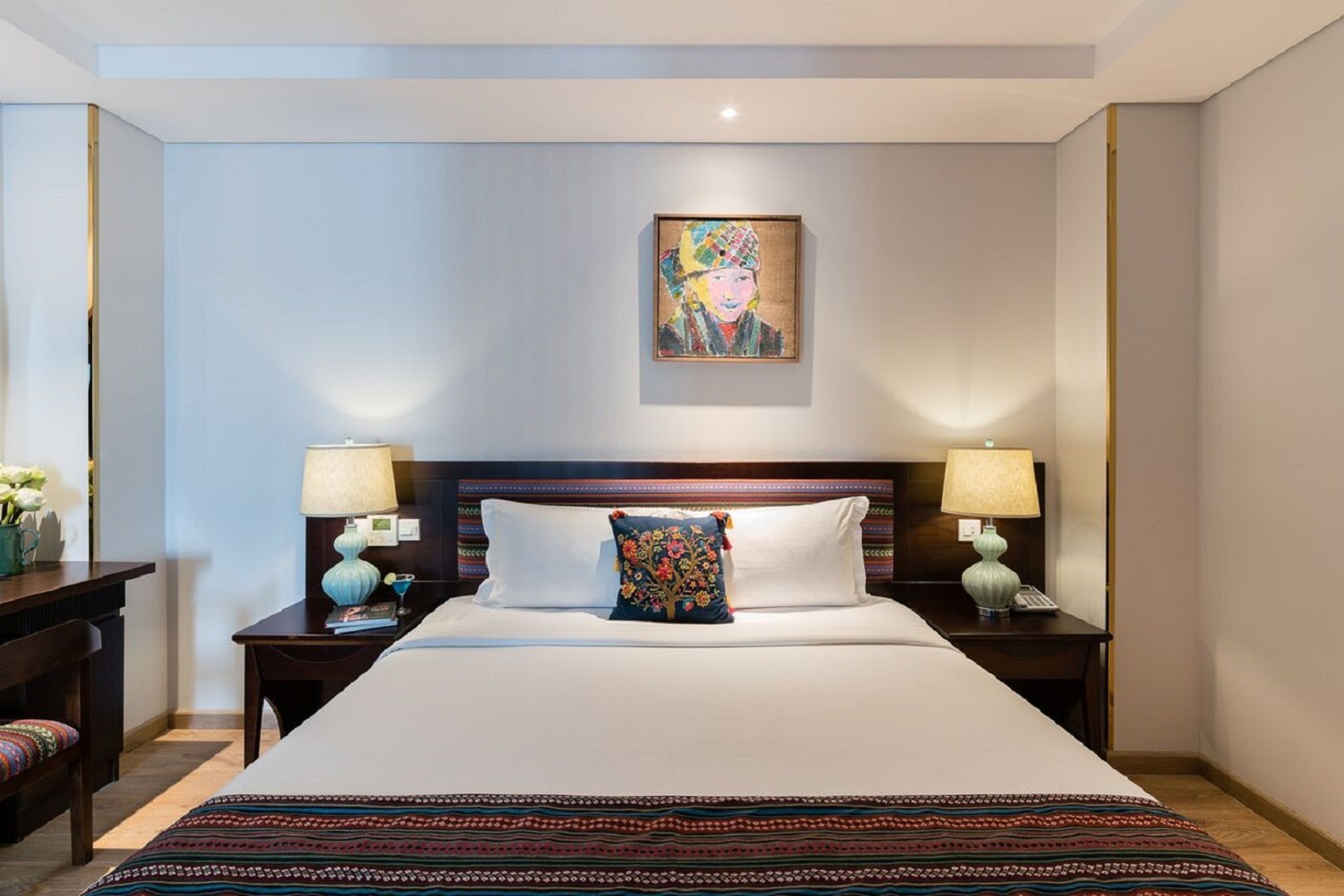 A hotel room with a large bed, two bedside tables, a nightstand, a desk, and a chair.