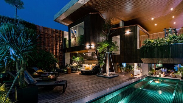 Ein modernes Haus mit Pool, Sitzgelegenheiten im Freien und einer gut beleuchteten Terrasse.