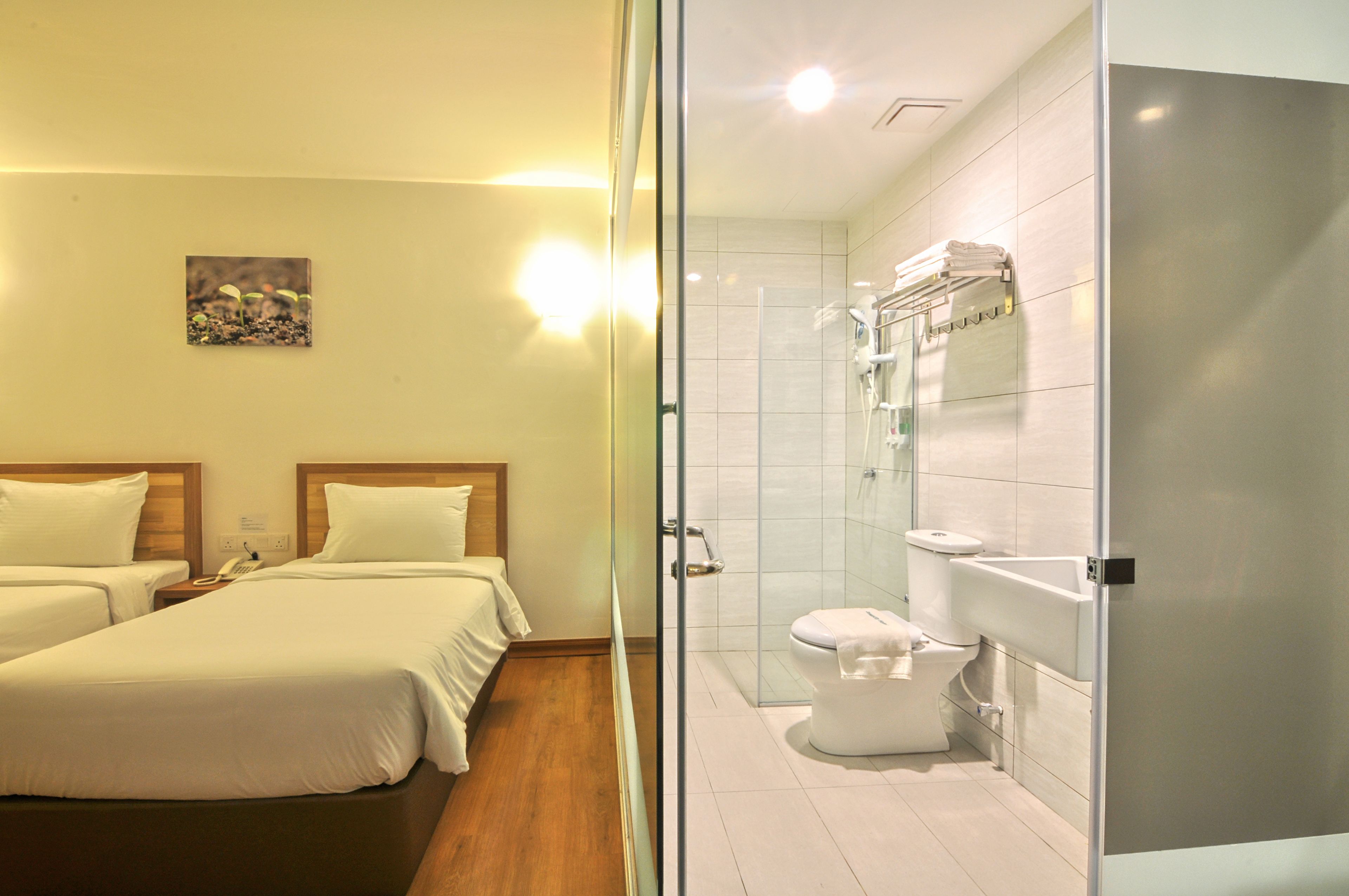 A hotel room with two beds, a shower, and a toilet.