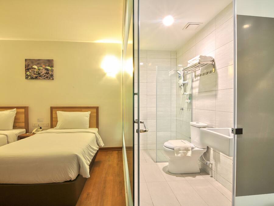 A hotel room with two beds, a shower, and a toilet.