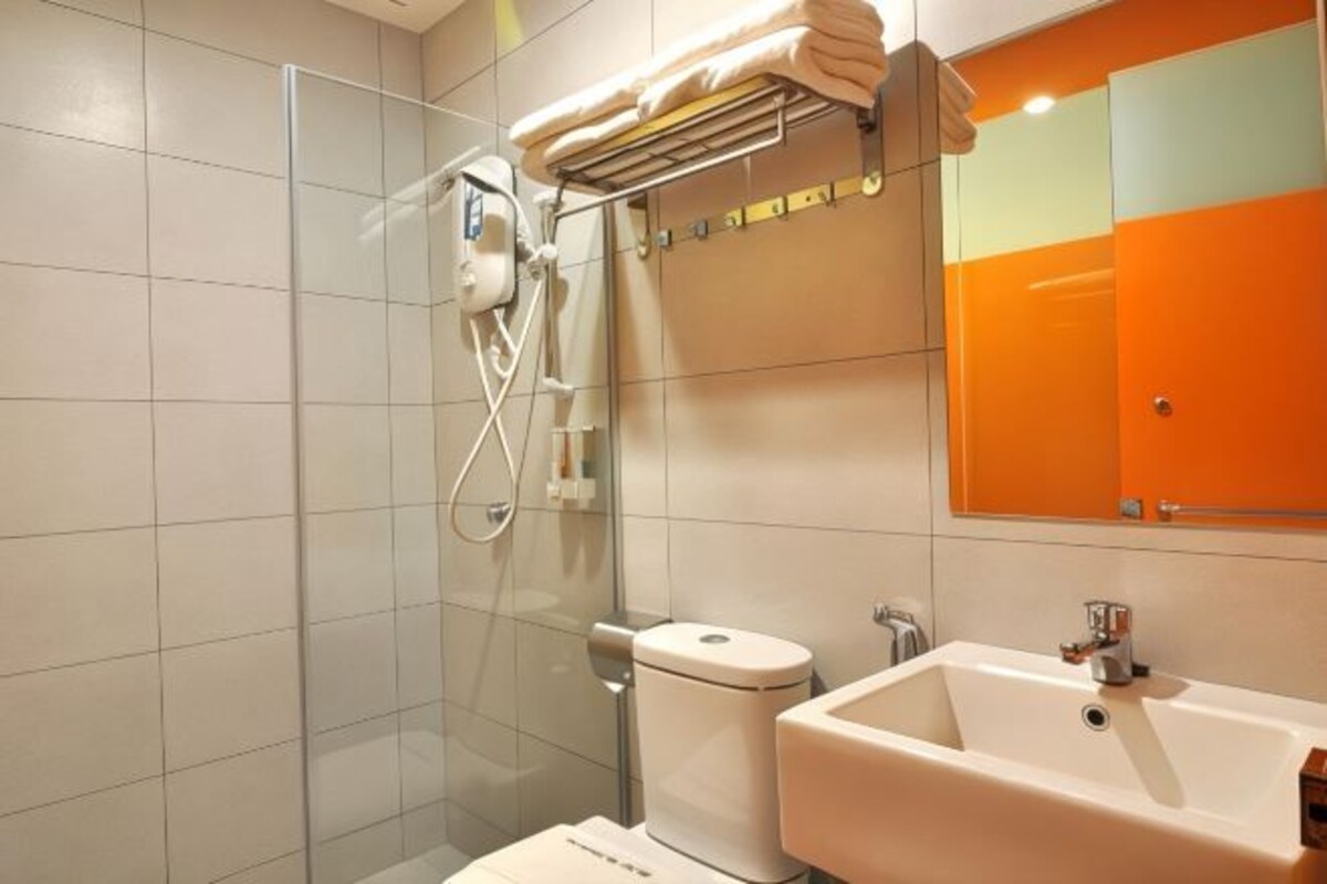 Un baño moderno con cabina de ducha de vidrio, inodoro y lavamanos.