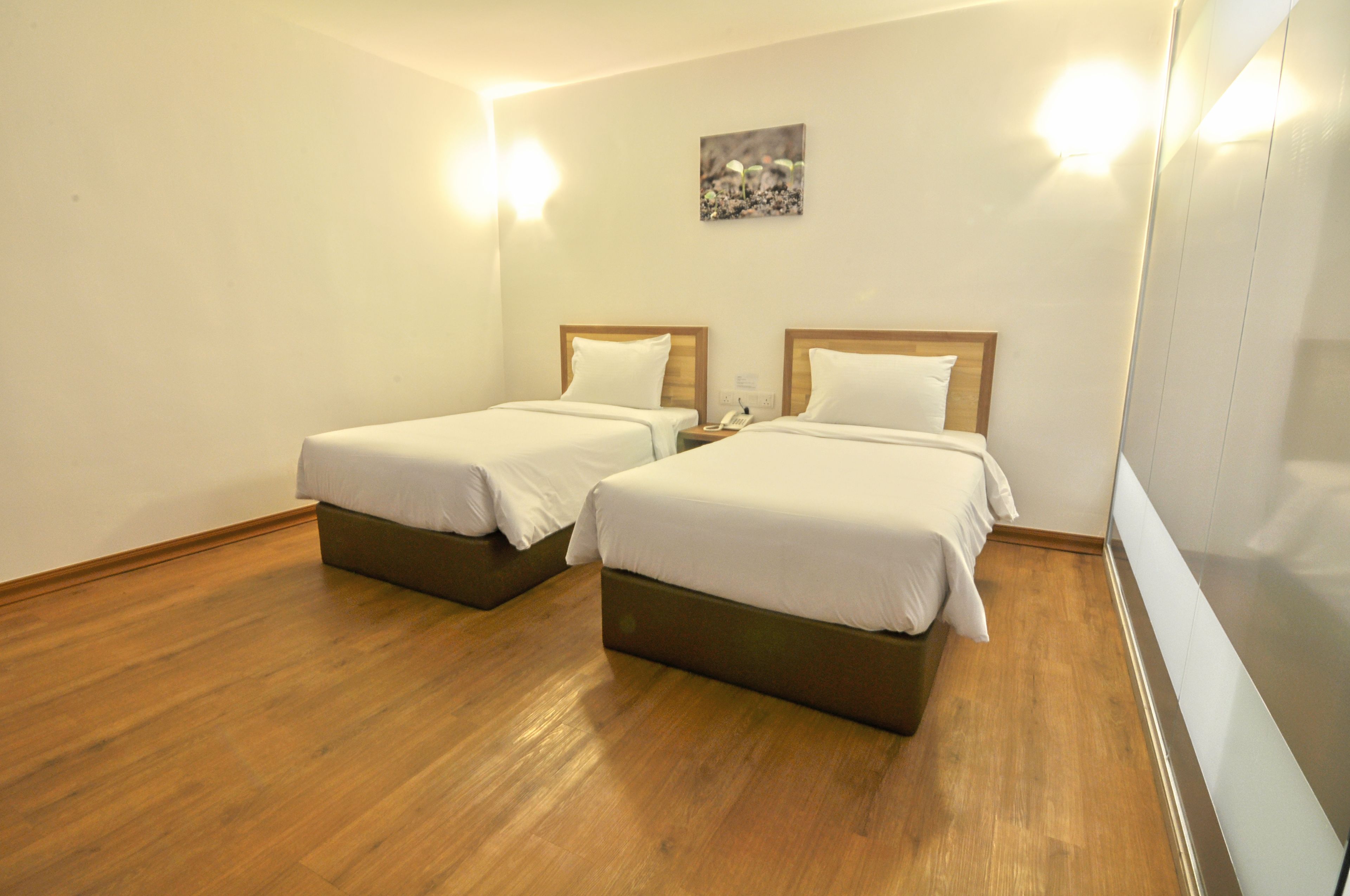 Ein Hotelzimmer mit zwei Betten, Holzboden und einem Bild an der Wand.