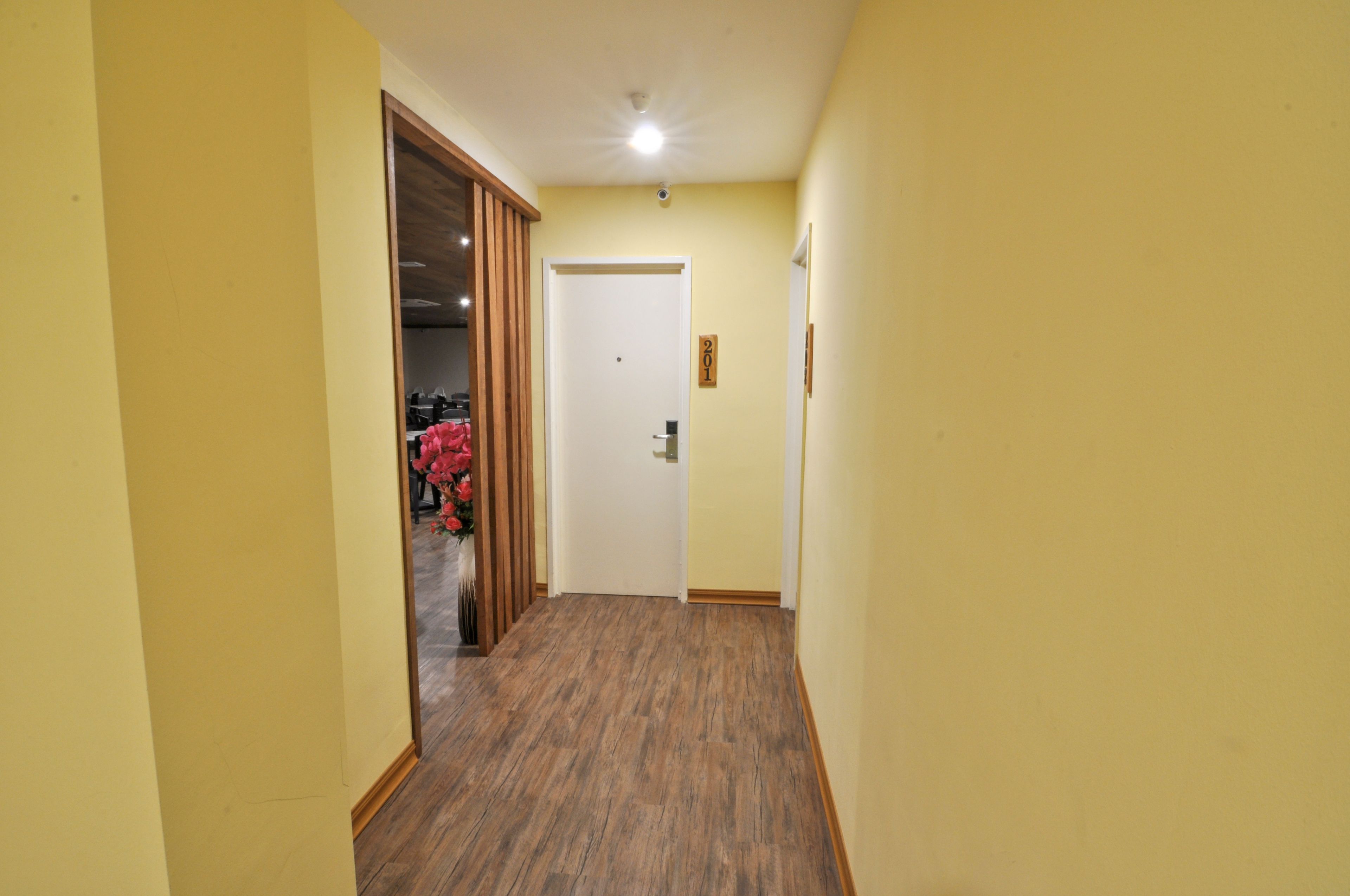 A narrow hallway with wooden flooring and yellow walls.