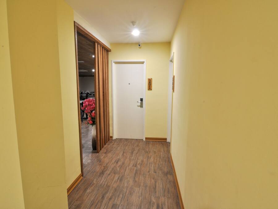 A narrow hallway with wooden flooring and yellow walls.