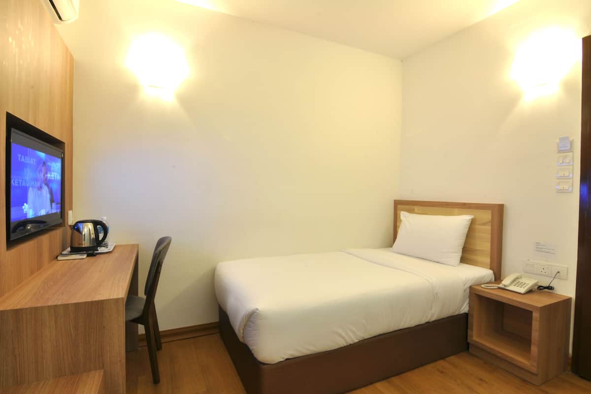 Une chambre d’hôtel comprenant un lit, un bureau avec une télévision, une chaise et une table de chevet avec un téléphone.