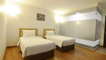 Habitación de hotel con dos camas, suelo de madera, un espejo grande y un cuadro pequeño en la pared.