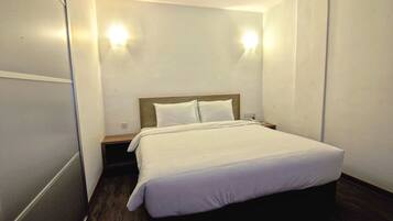 A hotel room with a bed, bedside table, and two wall-mounted lights.