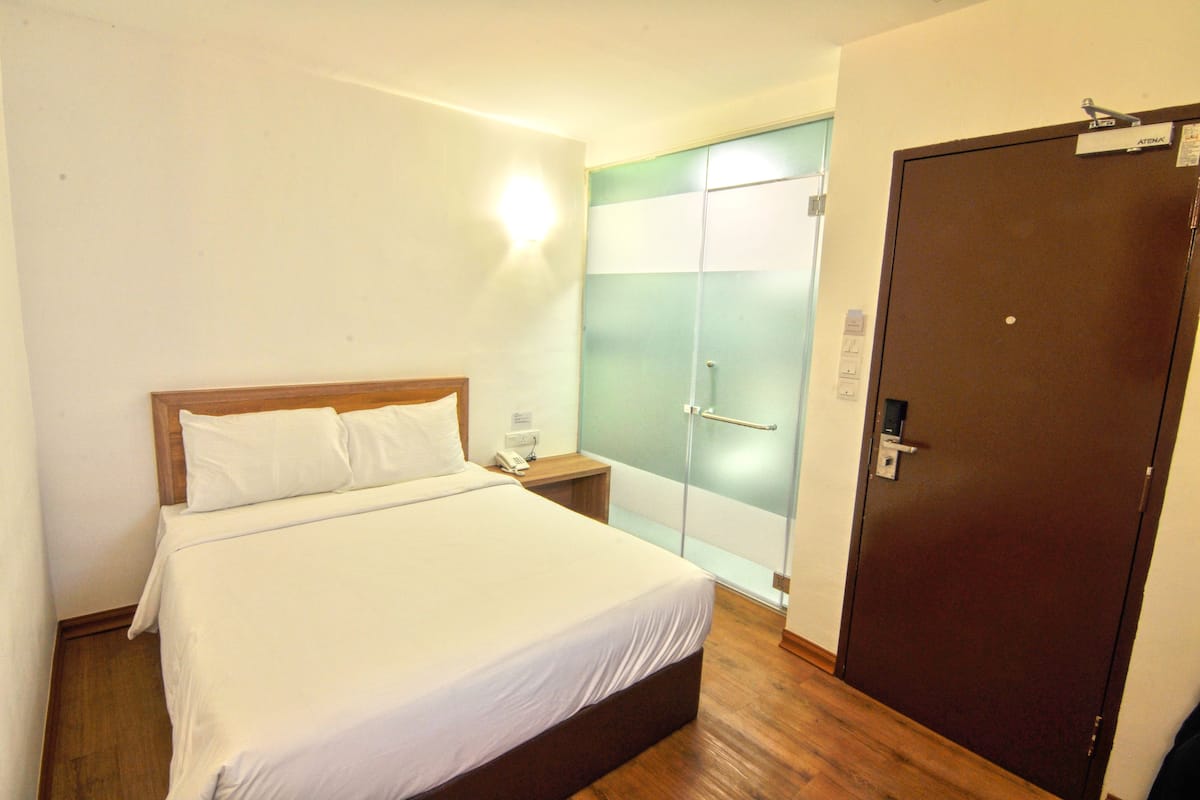 Une chambre d’hôtel avec un lit, une table de chevet et une armoire.