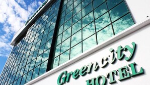 Het uiterlijk van Hotel Green City, met een heldere weerspiegeling van de lucht in de ramen.