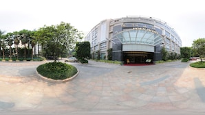 A hotel entrance with a curved facade, palm trees, and a tiled walkway. - Poly Hotel (Guangzhou)