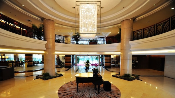 A spacious lobby with a central piano, multiple seating areas, and a large chandelier. - Poly Hotel (Guangzhou)