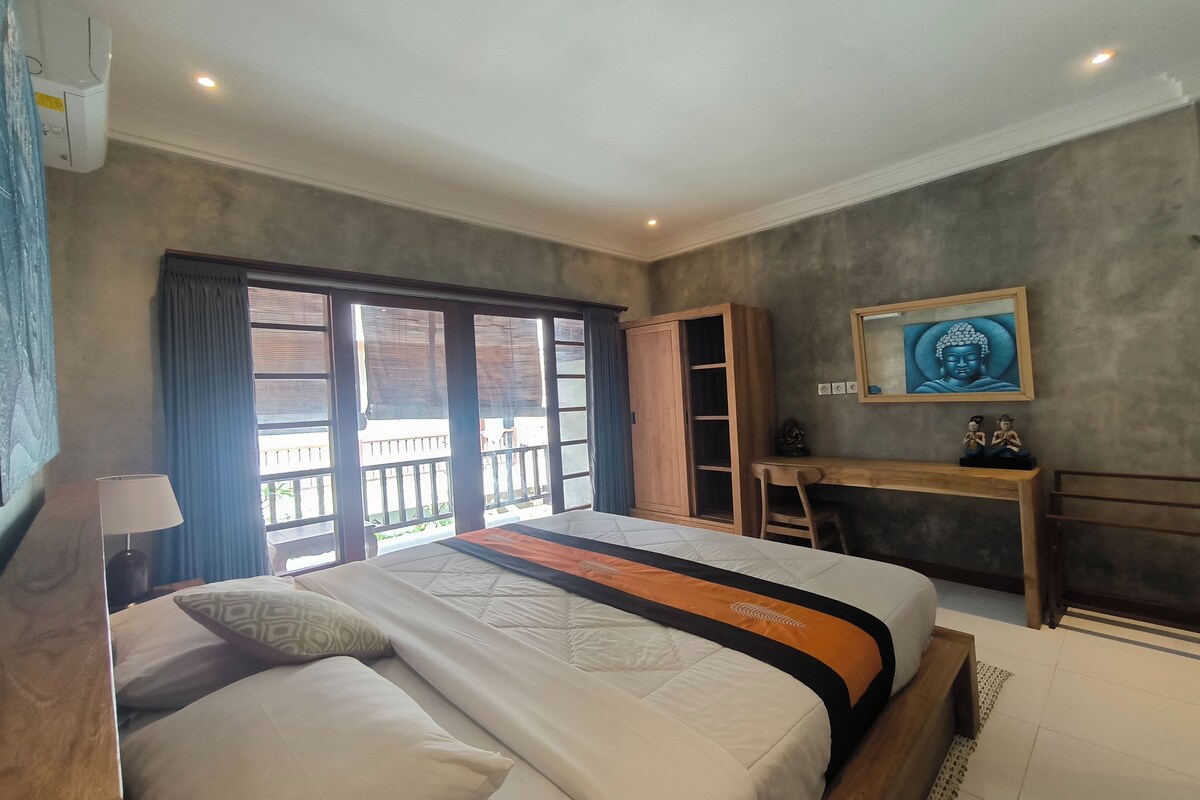 A hotel room with a large bed, a desk, and a view of the outside.