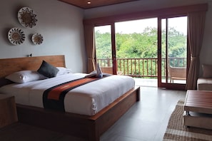Une chambre à coucher avec un grand lit, une tête de lit en bois et une vue sur un balcon doté d’une balustrade.