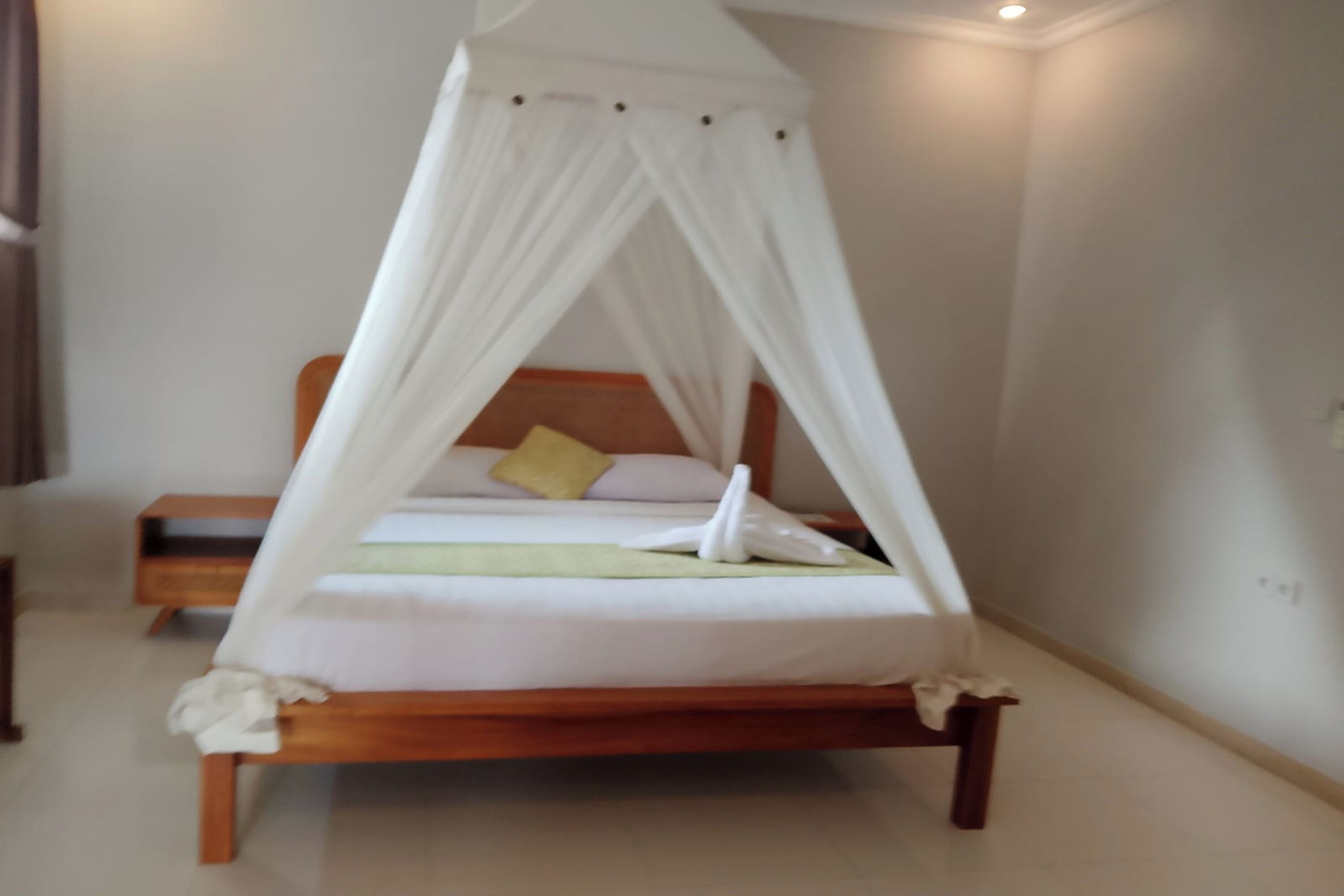 Un lit simple avec un baldaquin, une table de chevet et une petite table à côté du lit.