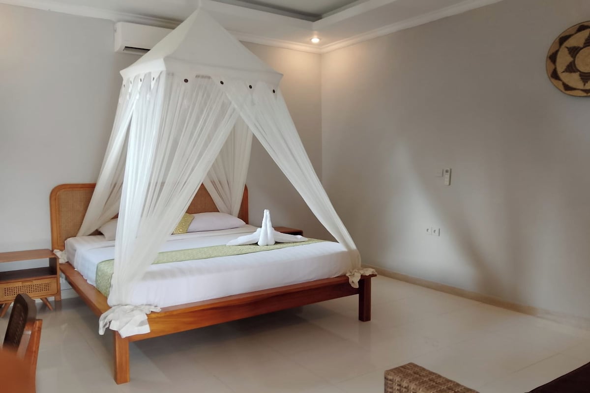 A wooden bed with a canopy, a bedside table, and a wall-mounted air conditioner.