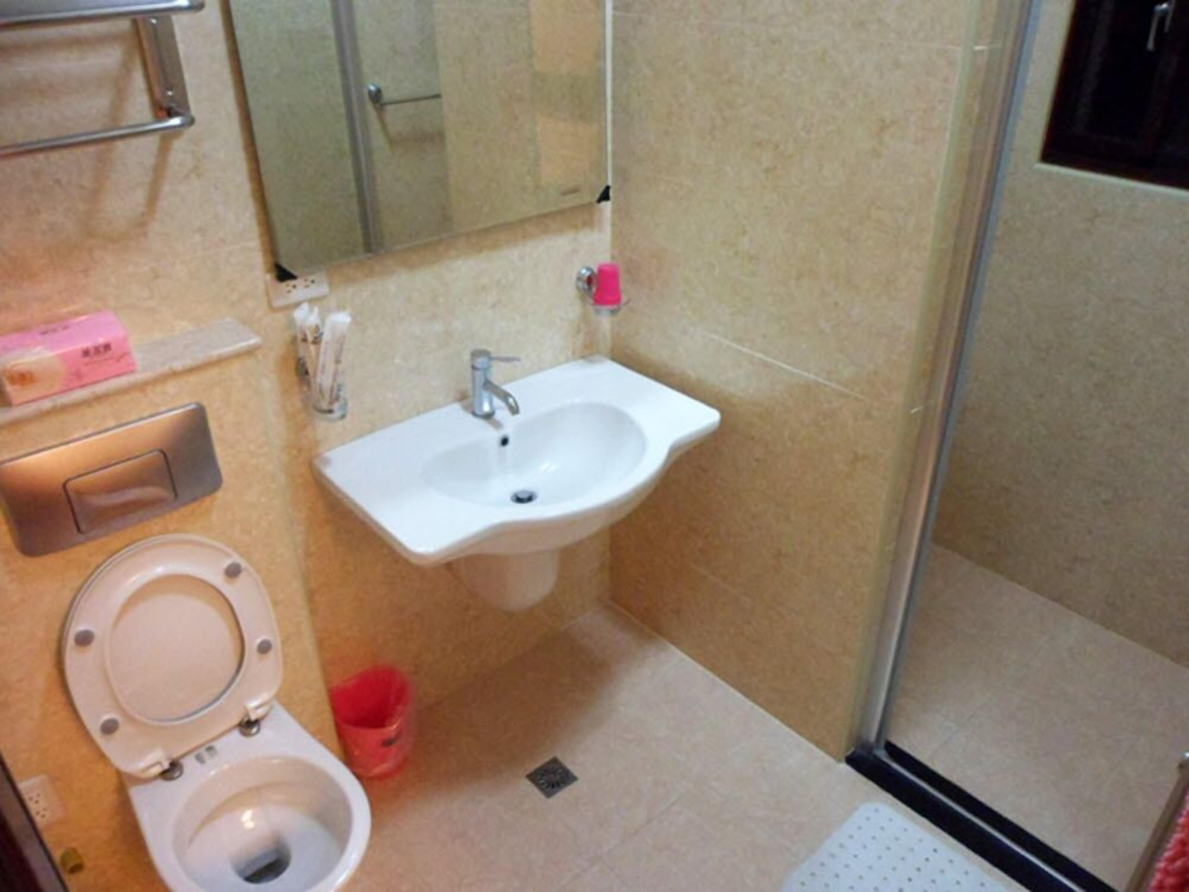 A small bathroom with a toilet, sink, and a mirror.