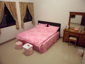 A bedroom with a bed, a dresser, a mirror, and a window with curtains.