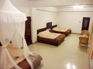 A room with two beds, a TV, a chair, and a wardrobe.