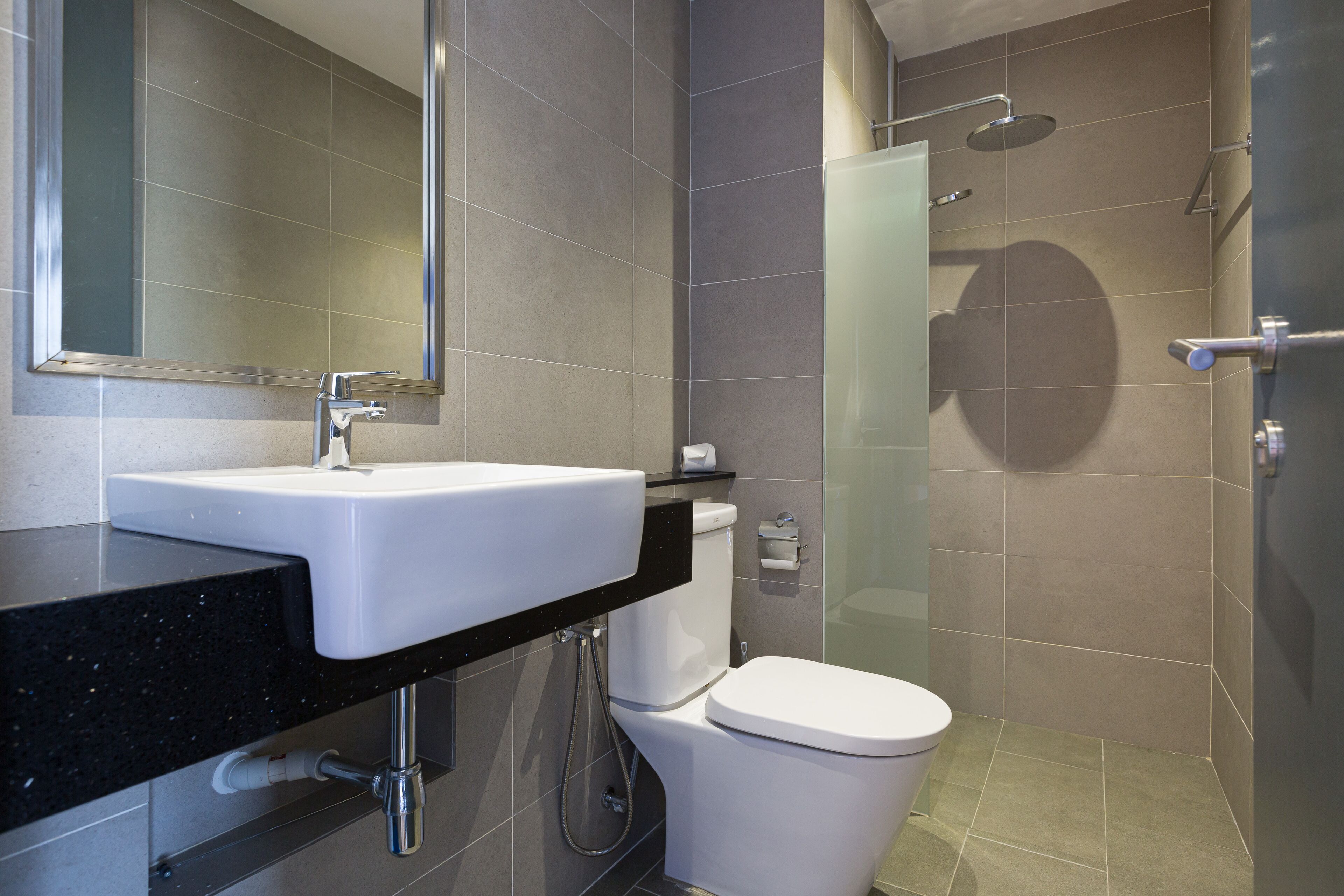 A modern bathroom with a sink, toilet, and shower.