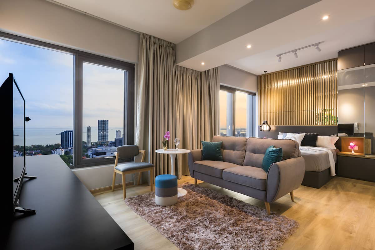 A modern living room with a sofa, ottoman, and a TV on a desk.