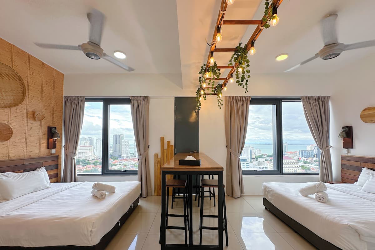 A hotel room with two beds, a dining table, and a view of the cityscape.